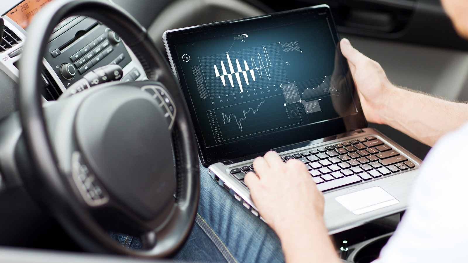 man using laptop computer in car